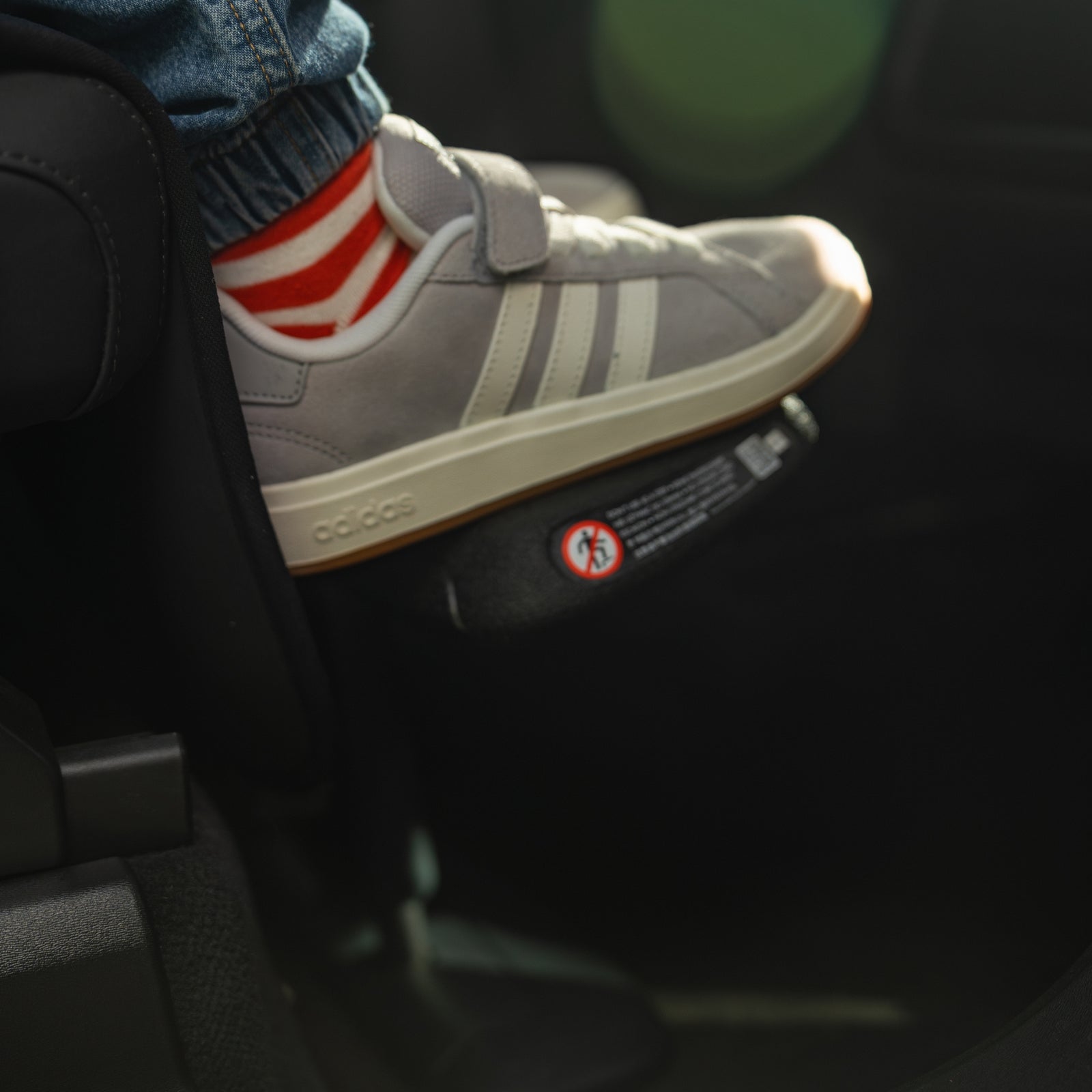 Close-up of child using the Swandoo universal footrest accessory inside a vehicle