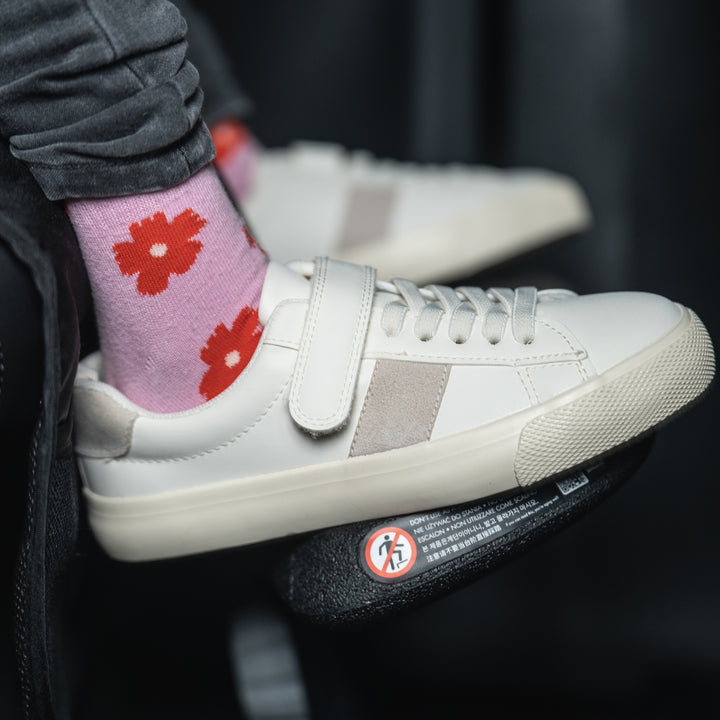 Close-up of child’s feet resting on the Swandoo universal footrest accessory inside a vehicle
