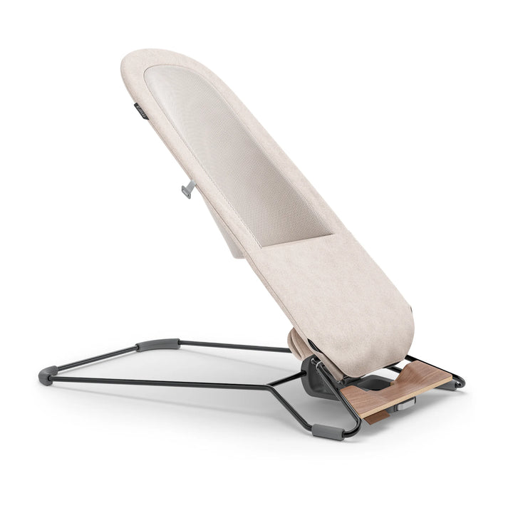 “UPPAbaby Mira Bouncer in Charlie beige shown in upright side profile, featuring breathable mesh backrest, ergonomic infant support, adjustable recline, and lightweight steel frame with wooden base detail.”