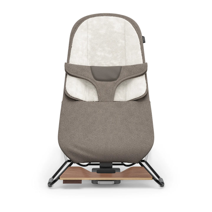 “UPPAbaby Mira Bouncer in Wells taupe shown front-facing on a white background, featuring plush newborn insert, breathable mesh support panel, ergonomic infant harness, and modern lightweight steel frame with walnut-tone wood base accent.”
