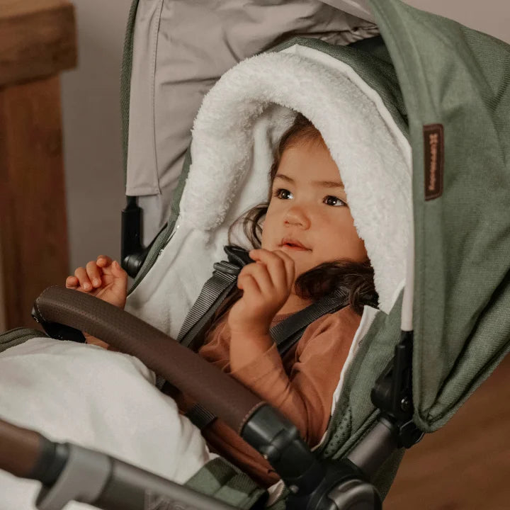 Child wrapped up with hood feature of the CozyGanoosh in the Vista V3 stroller.