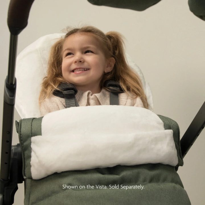 Toddler riding comfortably in an UPPAbaby stroller with the 2-in-1 Seasonal Cozy Ganoosh footmuff in green, featuring plush fleece lining for warmth and cosy cold-weather strolls.