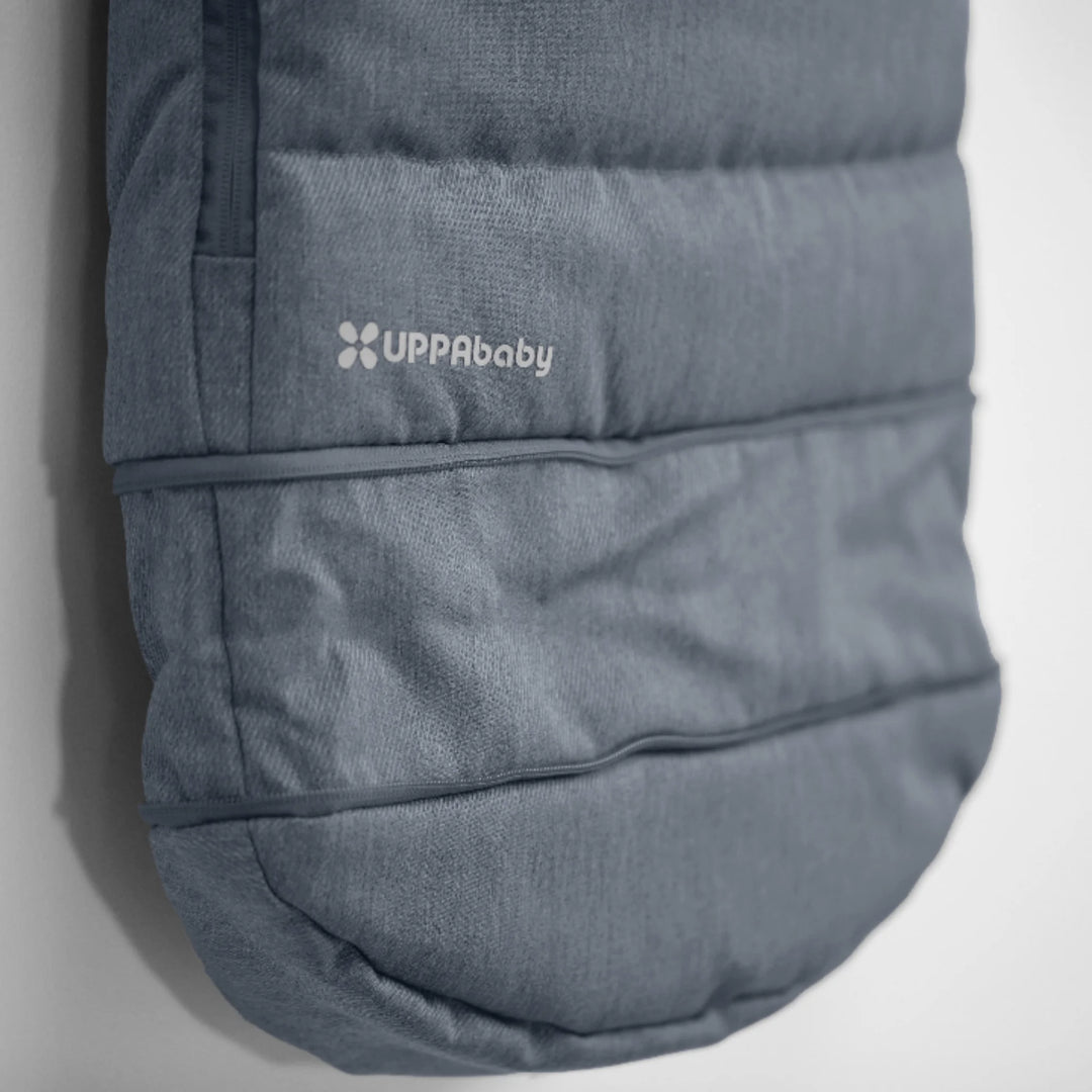 Close-up of UPPAbaby 2-in-1 Seasonal Cozy Ganoosh stroller footmuff in Julian blue showing quilted, insulated design with UPPAbaby logo, windproof and water-repellent fabric for cold weather pushchair use.