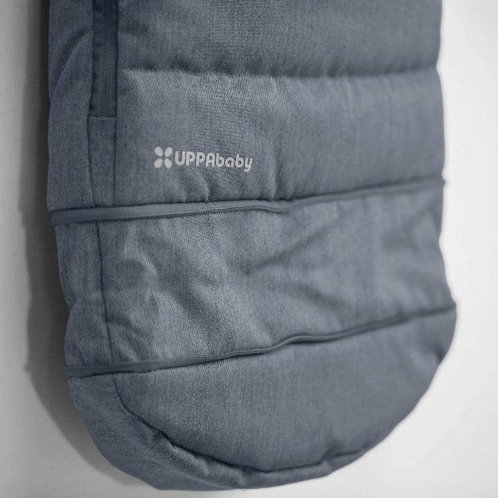 Close-up of UPPAbaby 2-in-1 Seasonal Cozy Ganoosh stroller footmuff in Julian blue showing quilted, insulated design with UPPAbaby logo, windproof and water-repellent fabric for cold weather pushchair use.