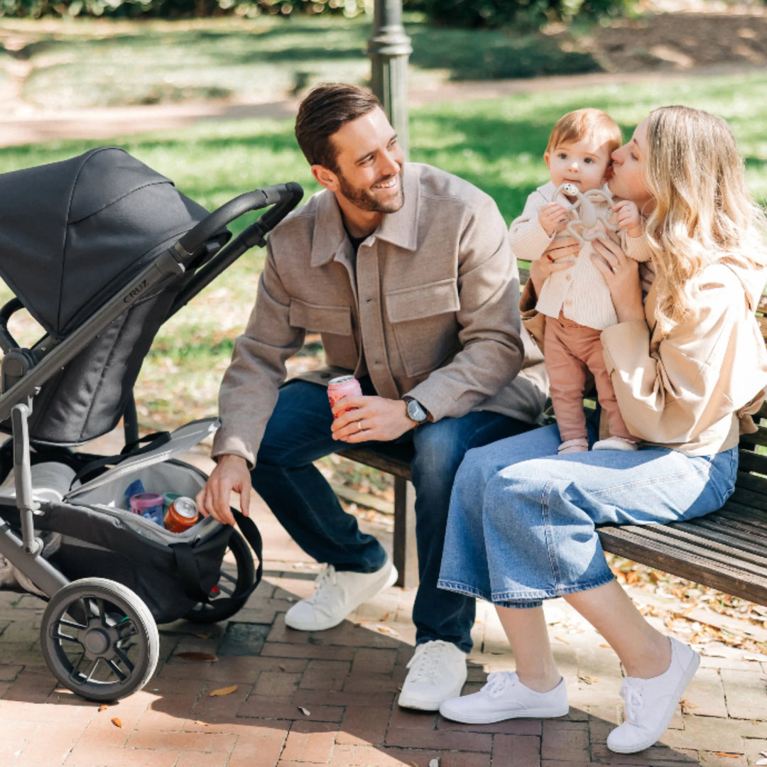 UPPAbaby Bevvy stroller basket cooler bag shown inside UPPAbaby pushchair basket during family day out, insulated cooler keeping drinks and snacks chilled.