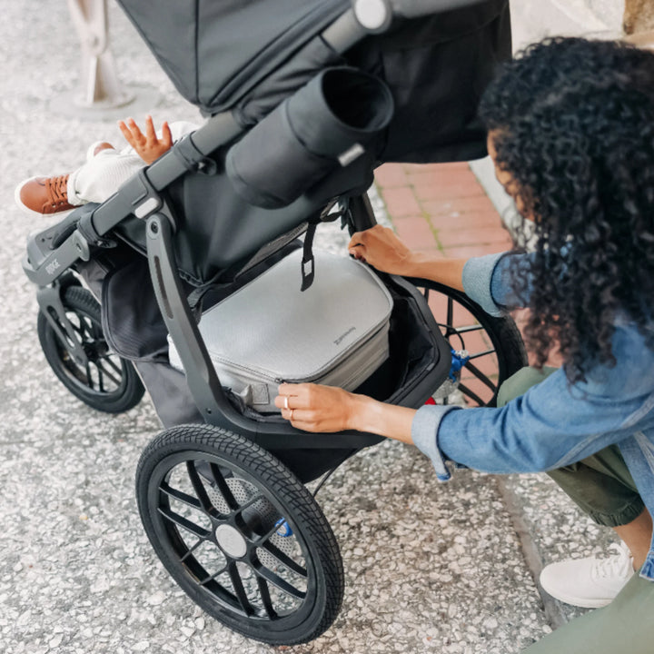 UPPAbaby Bevvy stroller basket cooler bag being fitted into pushchair basket, insulated cooler designed to keep food and drinks cold while out with baby.
