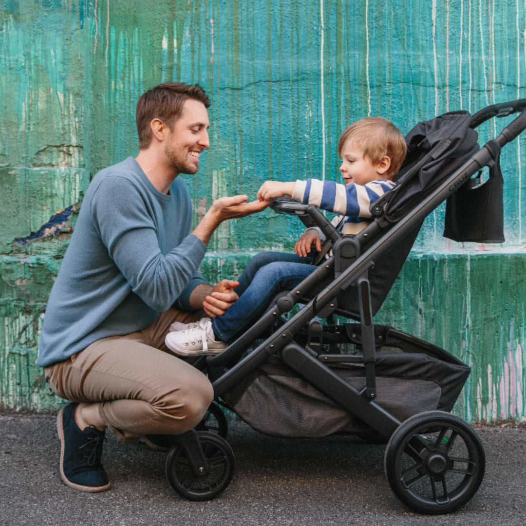 Dad with toddler in UPPAbaby stroller, featuring the UPPAbaby Carry-All Parent Stroller Organiser for drinks and essentials