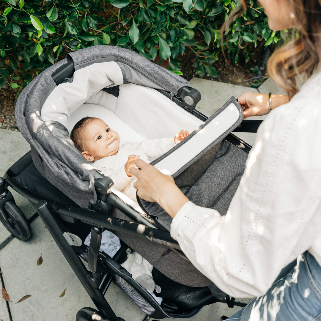 This image shows a Mum opening the boot cover on the Carrycot V3 with the dual zipper for easy access.