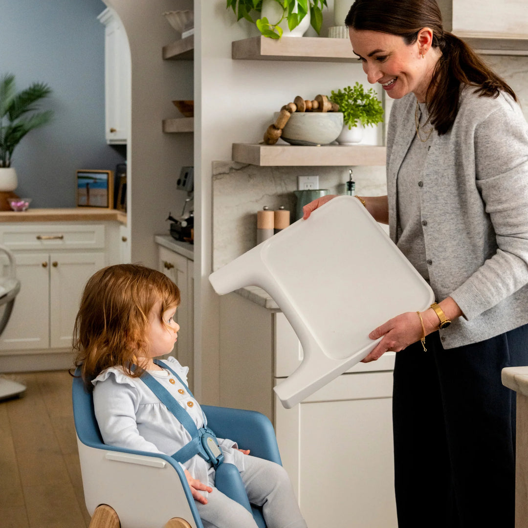 Woman setting up a high chair for a child in a kitchen.