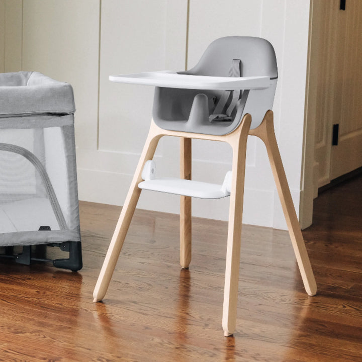 UPPAbaby Ciro High Chair Chloe in modern home setting, featuring minimalist grey seat, wooden legs, adjustable tray and footrest for babies and toddlers.