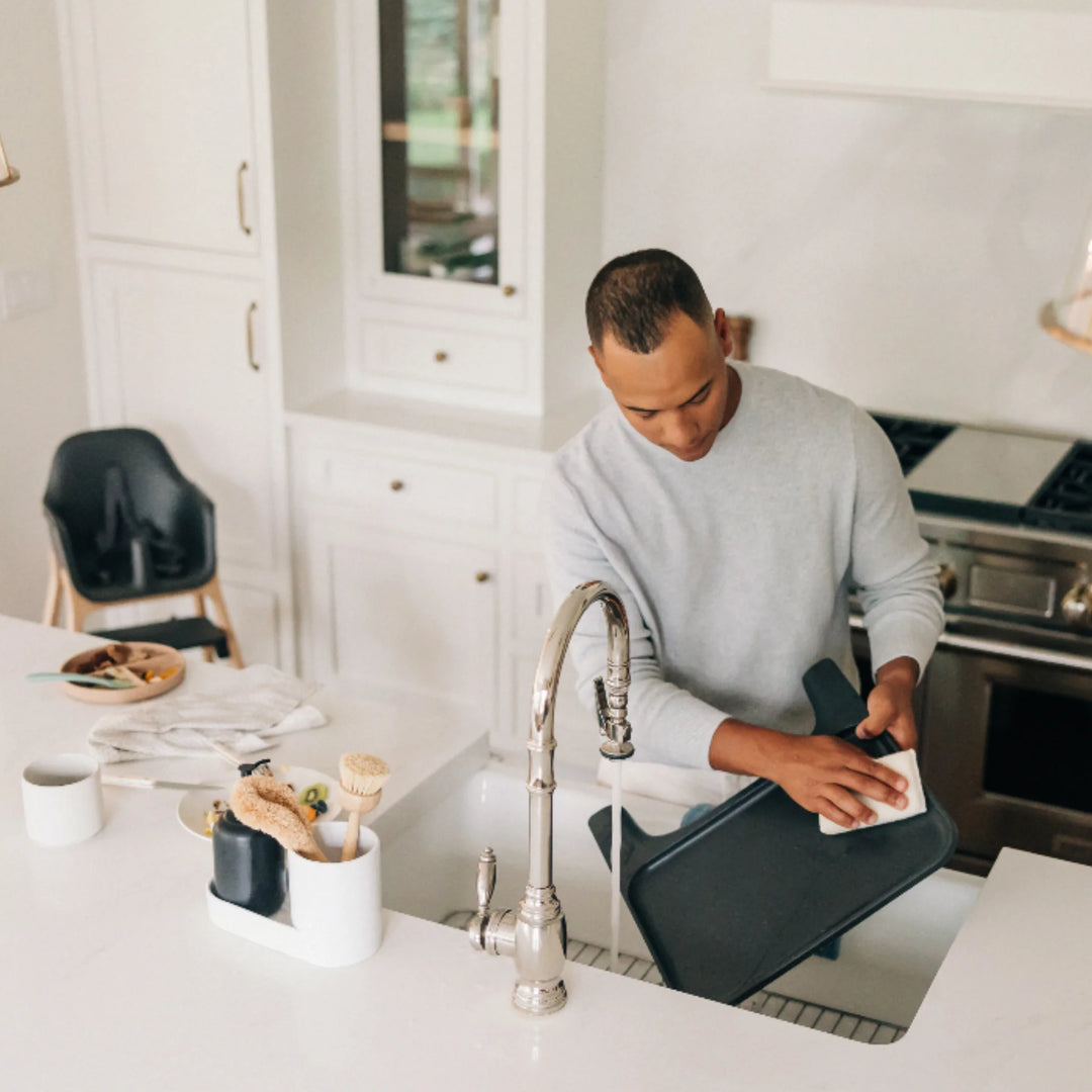 Dad cleaning UPPAbaby Ciro High Chair Jake tray in modern kitchen, demonstrating easy-to-clean, removable high chair tray for hassle-free baby mealtime cleanup.