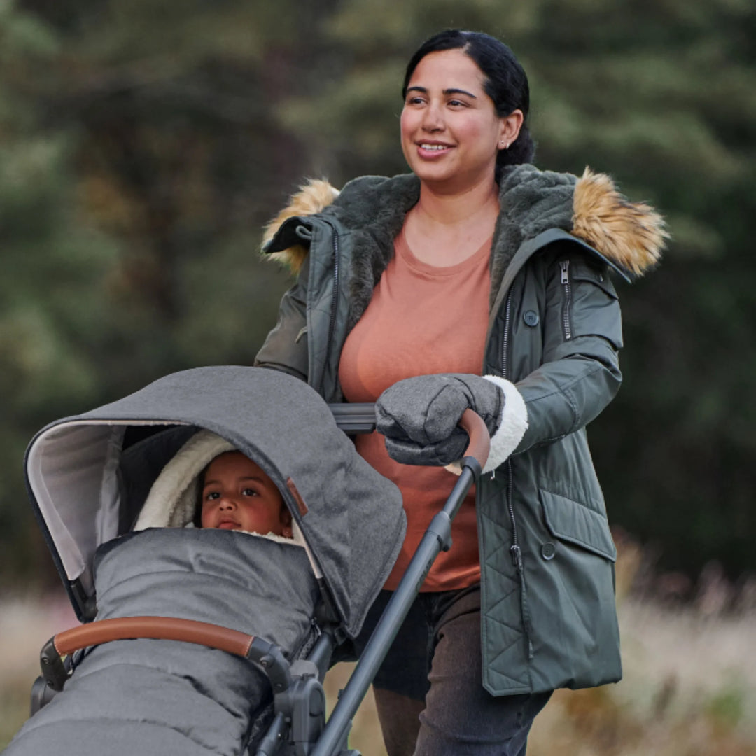 Parent pushing a stroller using UPPAbaby Cozy Handmuffs in Greyson, fleece-lined stroller hand warmers providing warmth and comfort during cold-weather walks with baby.