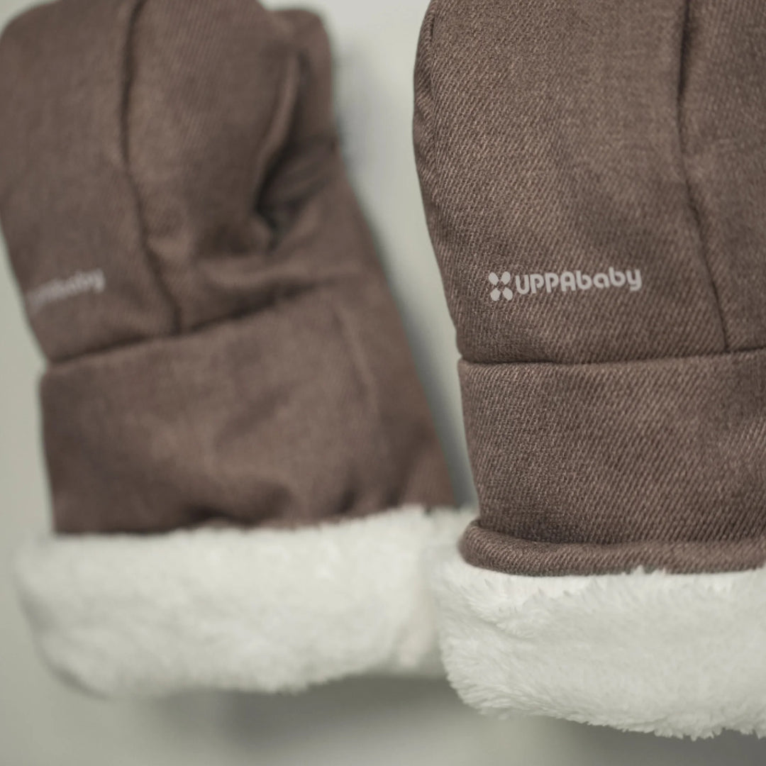 Close-up of UPPAbaby Cozy Handmuffs Owen in brown, showing soft fleece lining and durable outer fabric with UPPAbaby logo, designed as insulated stroller hand warmers for cold weather walks.