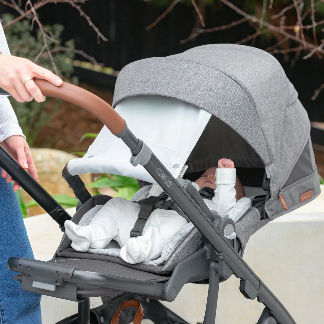 UPPAbaby Cruz V3 in Greyson with newborn lying in seat with extra sunshade in use.