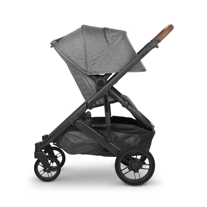 “UPPAbaby Cruz V2 Greyson stroller in side profile – grey premium pushchair with fully extended canopy, leather handlebar, and large storage basket designed for modern parents on the go.