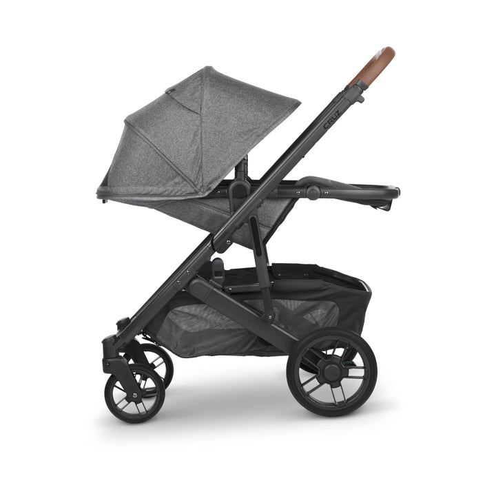 UPPAbaby Cruz V2 Greyson stroller in side view – modern grey pushchair with leather handlebar, toddler seat in parent-facing position, and large storage basket for everyday convenience.
