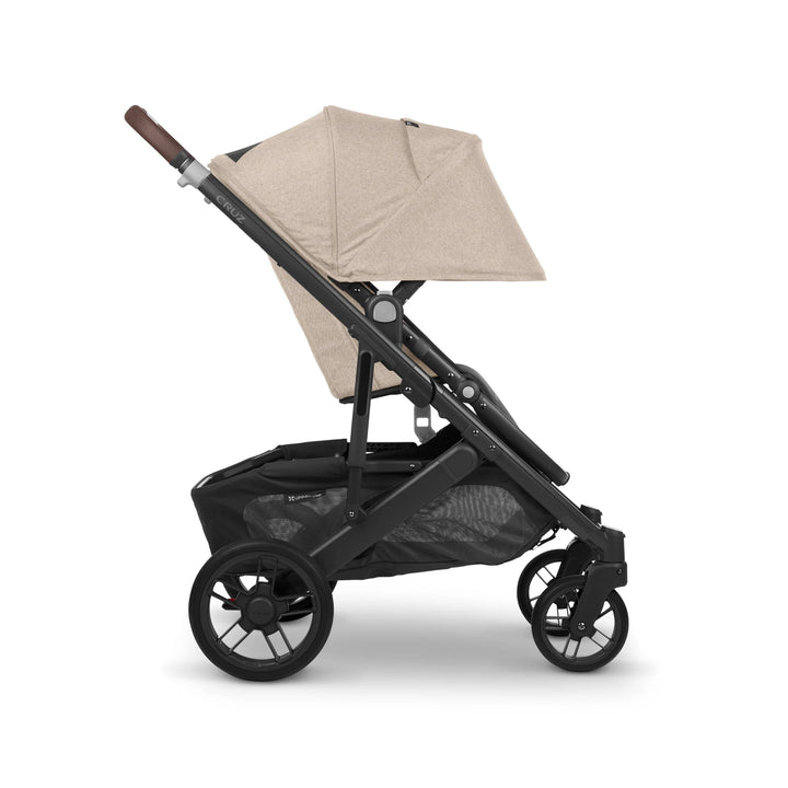 Side view of UPPAbaby Cruz V2 Liam stroller – beige pushchair with leather handlebar, adjustable canopy, and large storage basket designed for modern parents and everyday comfort