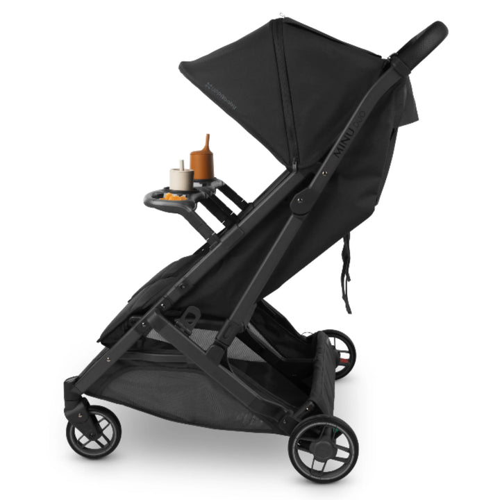 Side view of UPPAbaby Minu Duo Jake black double stroller with snack tray accessory and cup holder attached, on white background