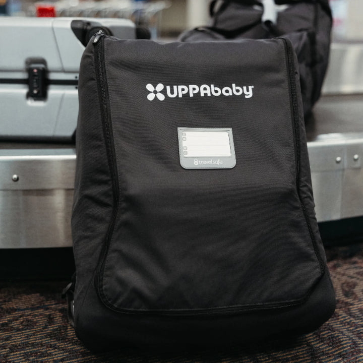 UPPAbaby Minu stroller travel bag standing at the airport beside luggage, ready for travel.