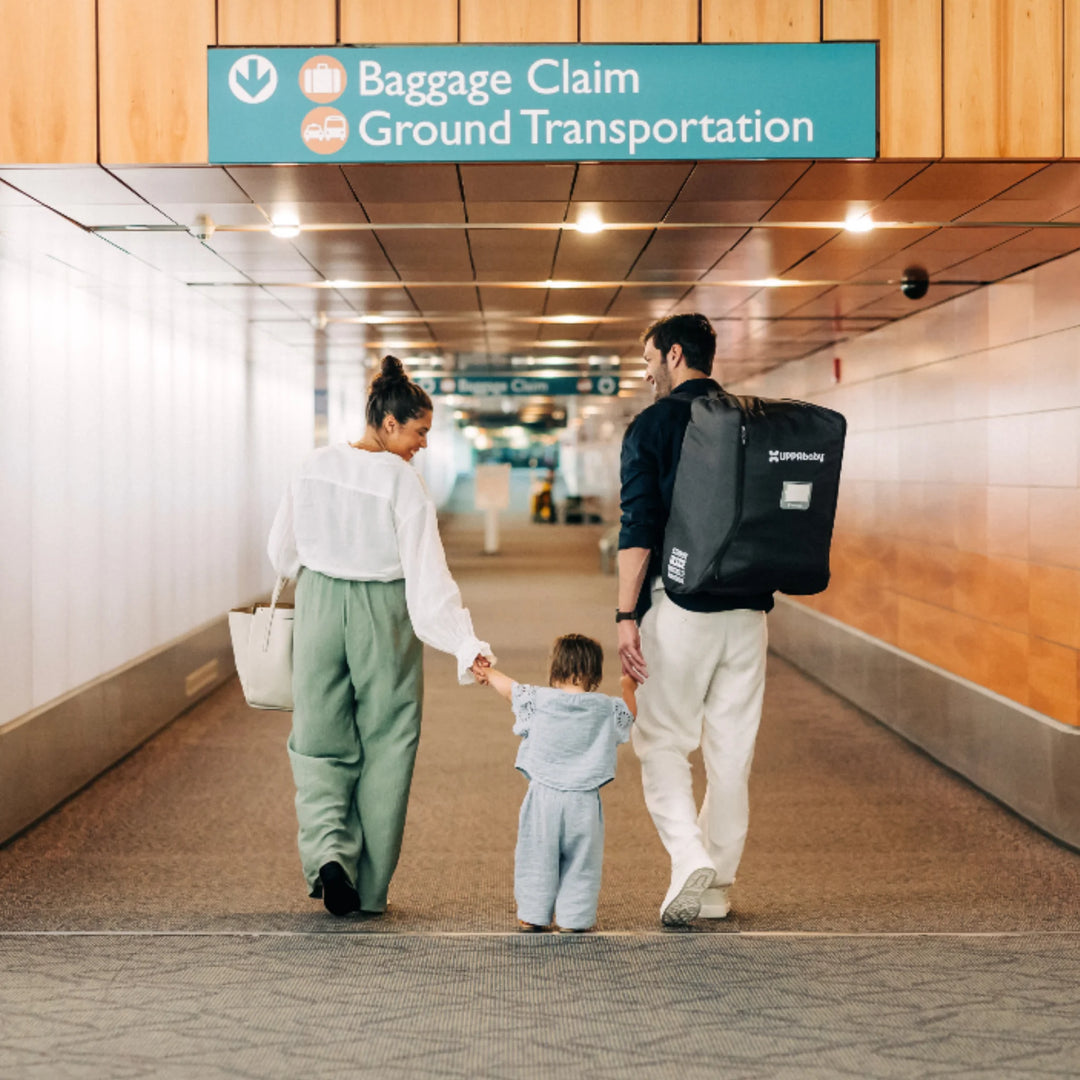 “Family walking through an airport with the UPPAbaby Minu stroller travel bag worn as a backpack.”