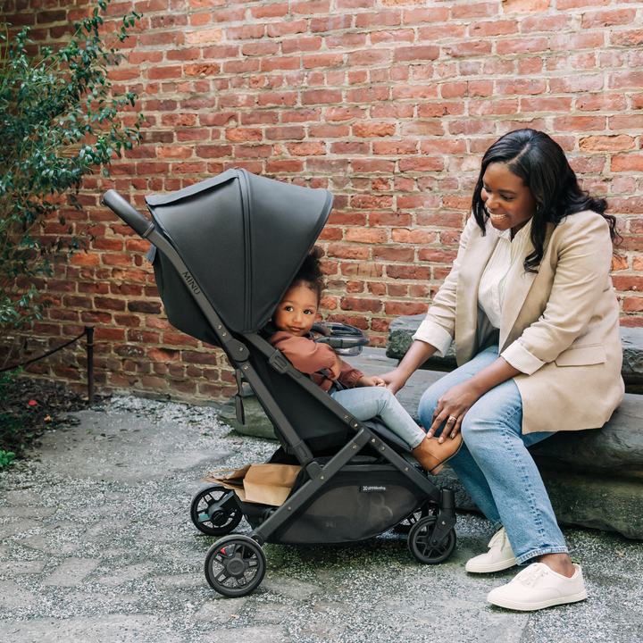 UPPAbaby Minu V2 snack tray lifestyle image with smiling child looking out of the stroller
