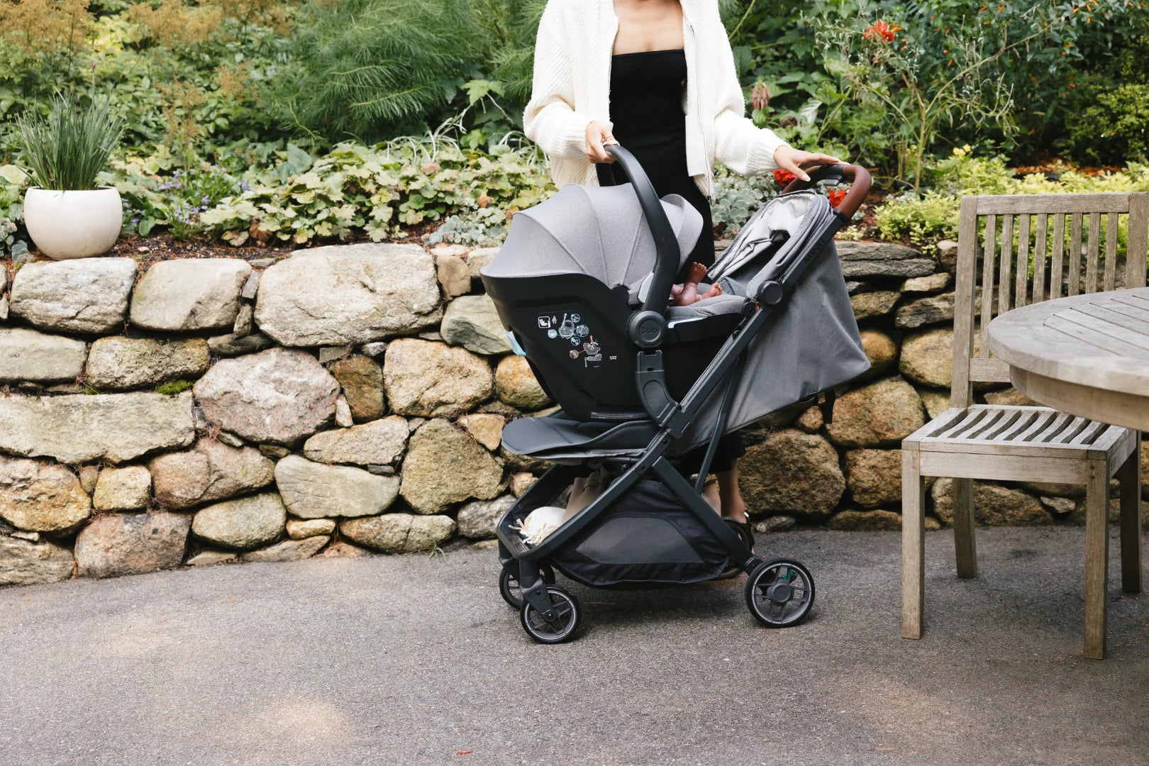 This image shows a parent standing behind the Minu V3 in Greyson attaching the car seat to the stroller.