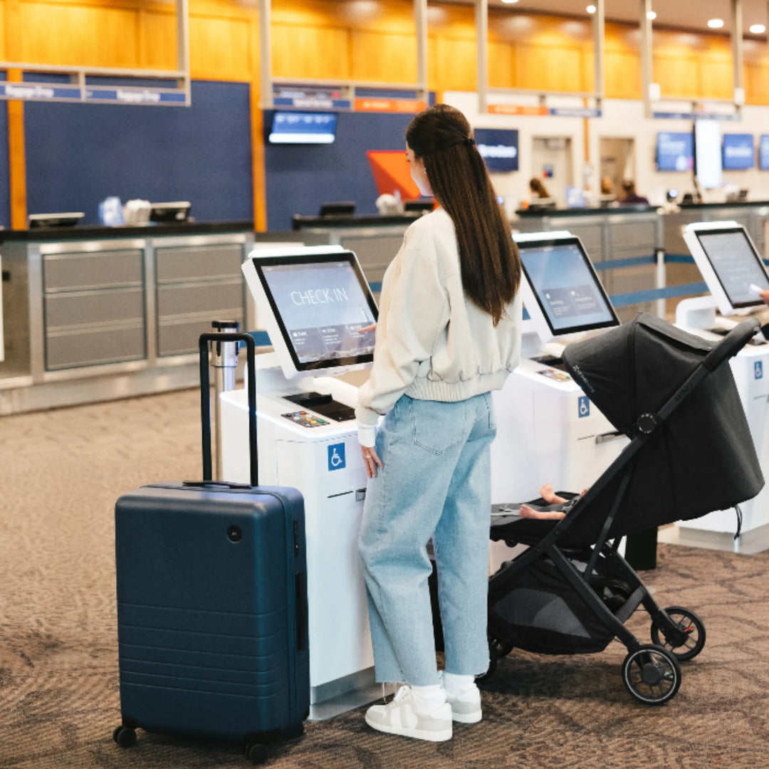 UPPAbaby MINU V3 Jake lightweight travel stroller at airport check-in with parent and suitcase