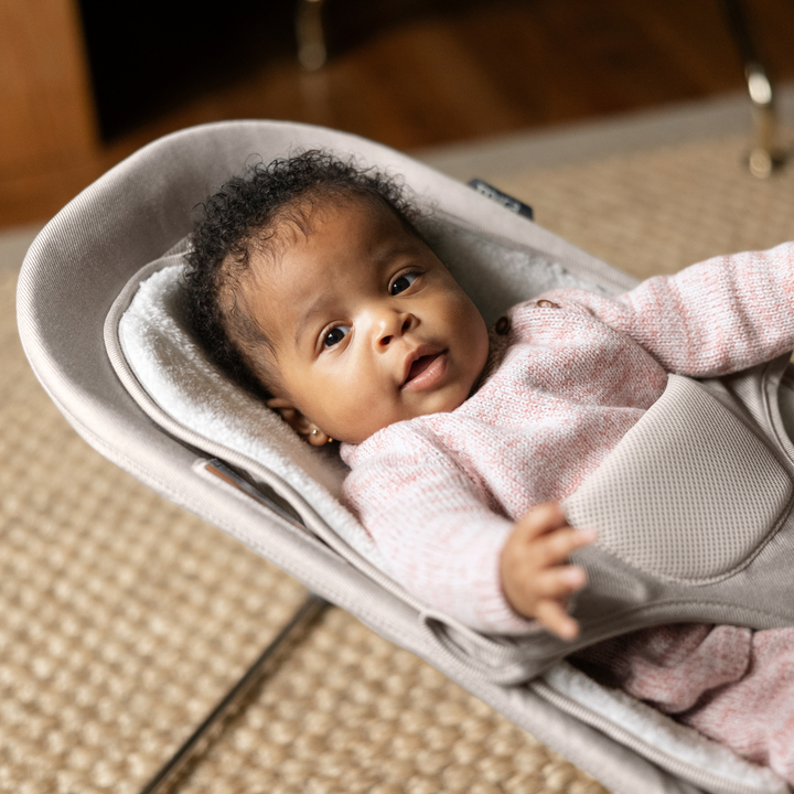 This is a lifestyle shot of the Mira bouncer in Charlie with a cute baby lying in the bouncer