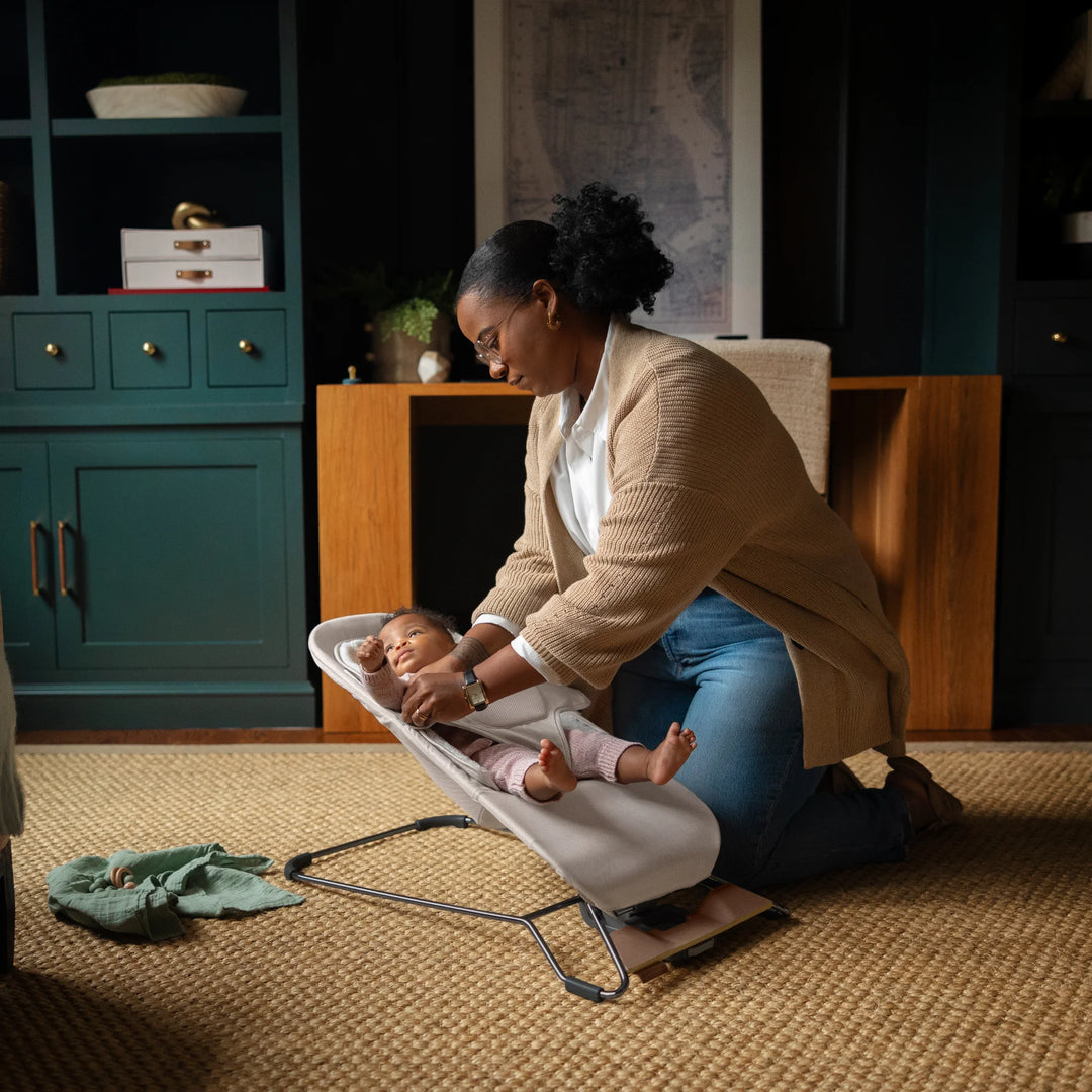 Mum securing baby in bouncer on the floor of her home office.