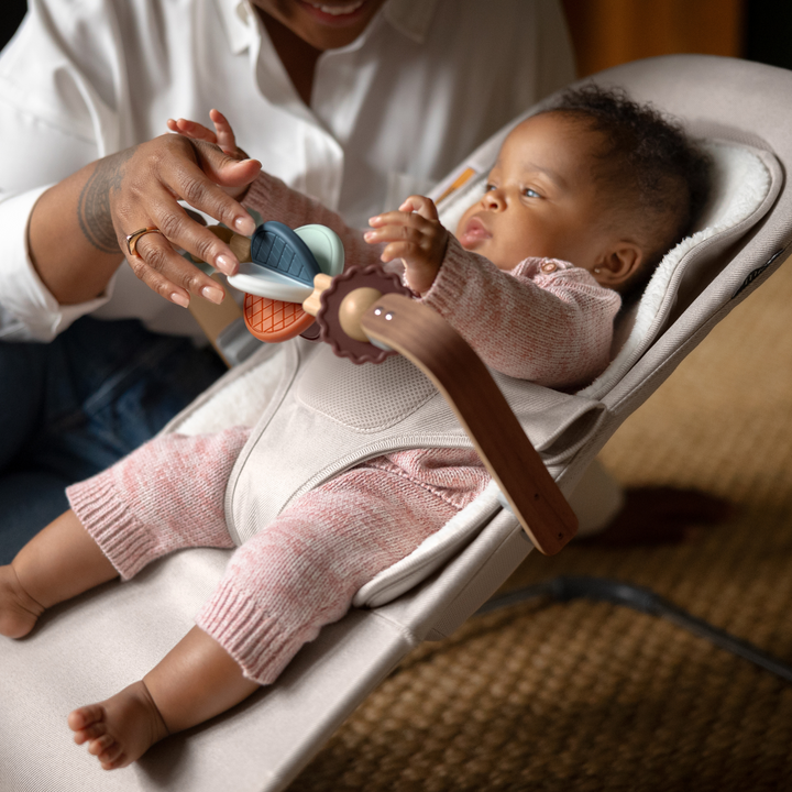 This is a lifestyle shot of a mom playing with the wonder wheel toy bar with her baby