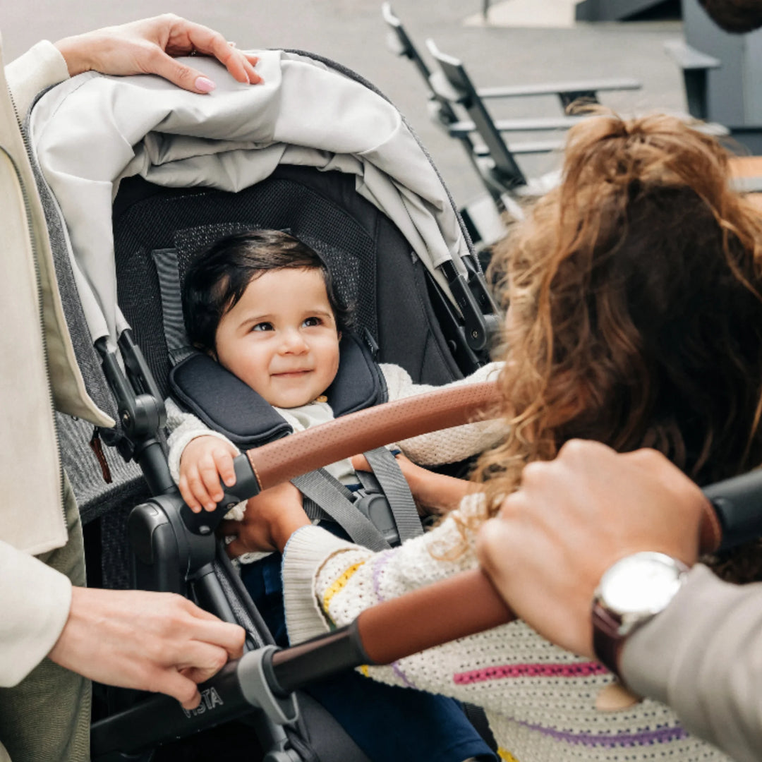 “Child sitting in UPPAbaby Vista V3 stroller, family using Vista pushchair with PiggyBack ride-along board”