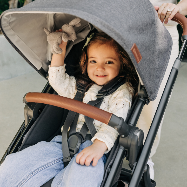 This image shows a smiling toddler holding on to a teddy in the toddler seat of the Vista V3.