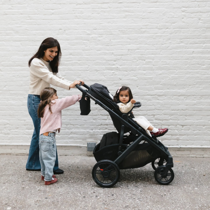 Mum pushing UPPAbaby Vista V3 stroller in Jake with Carry-All Parent Organiser and Snack Tray, two children walking together.