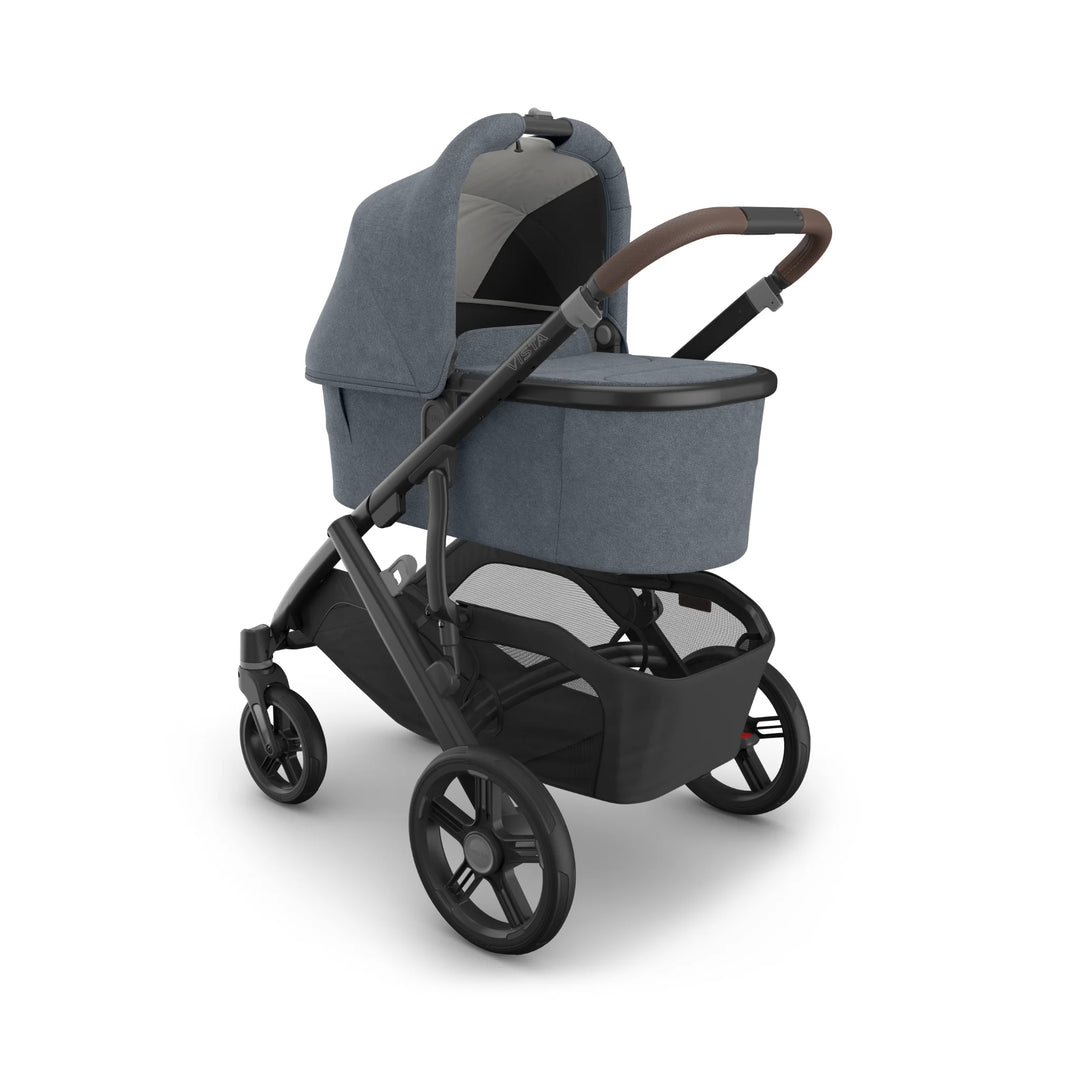 UPPAbaby Vista V3 stroller in Jullian blue with newborn bassinet attached, shown in a studio product image highlighting the extendable canopy, leather handlebar, durable all-terrain wheels and spacious under-seat storage basket on the premium Vista travel system.