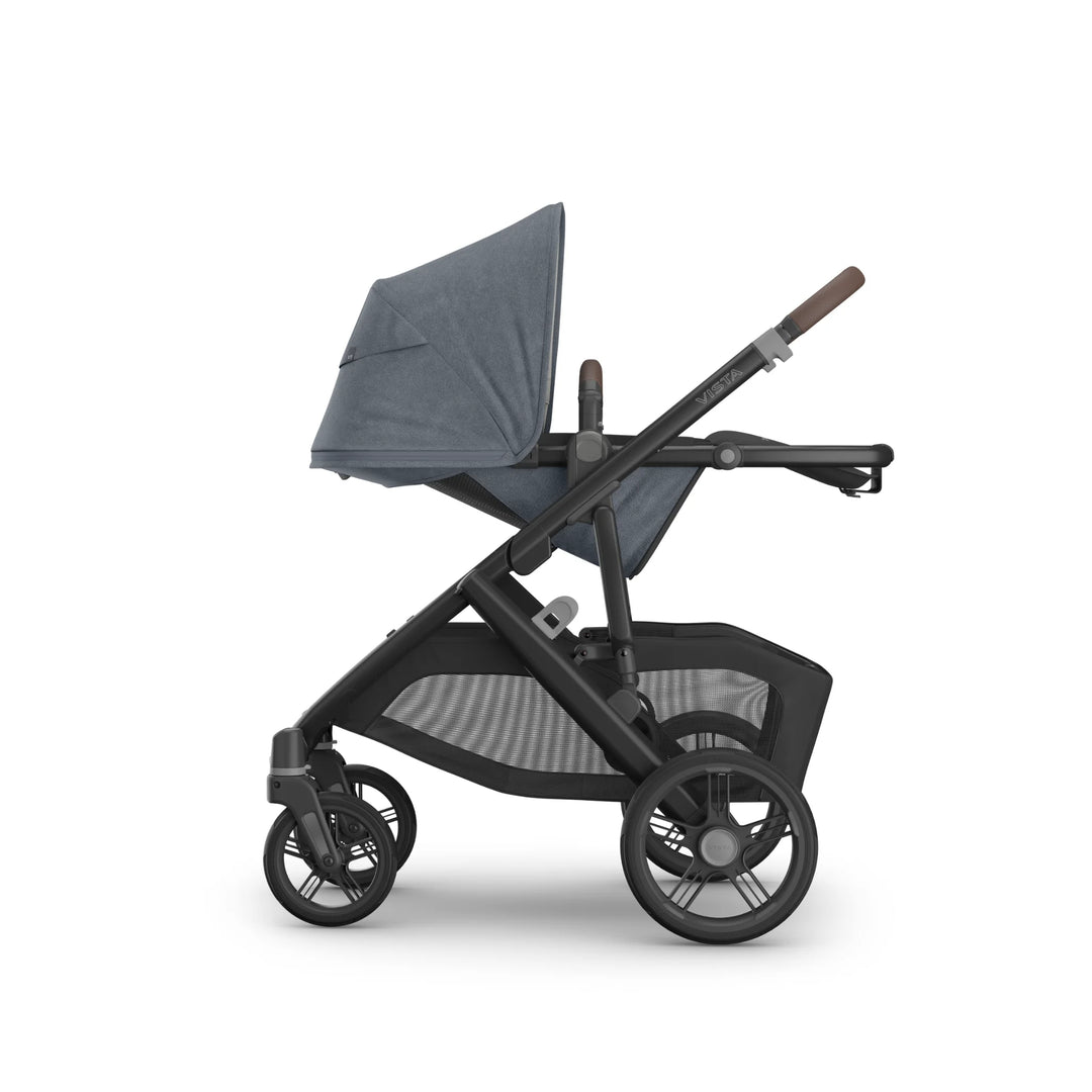 Side view of the UPPAbaby Vista V3 stroller in Jullian blue with the toddler seat fully reclined, showing the extended canopy, adjustable handlebar, durable all-terrain wheels and large mesh storage basket on the premium Vista travel system.