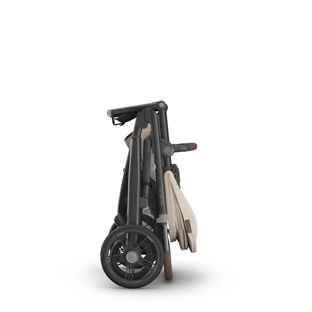 UPPAbaby Vista V3 stroller in the Liam oatmeal colourway shown folded in a compact upright position, highlighting its one-step fold mechanism, sturdy all-terrain wheels, leather-accented handlebar and space-saving design.