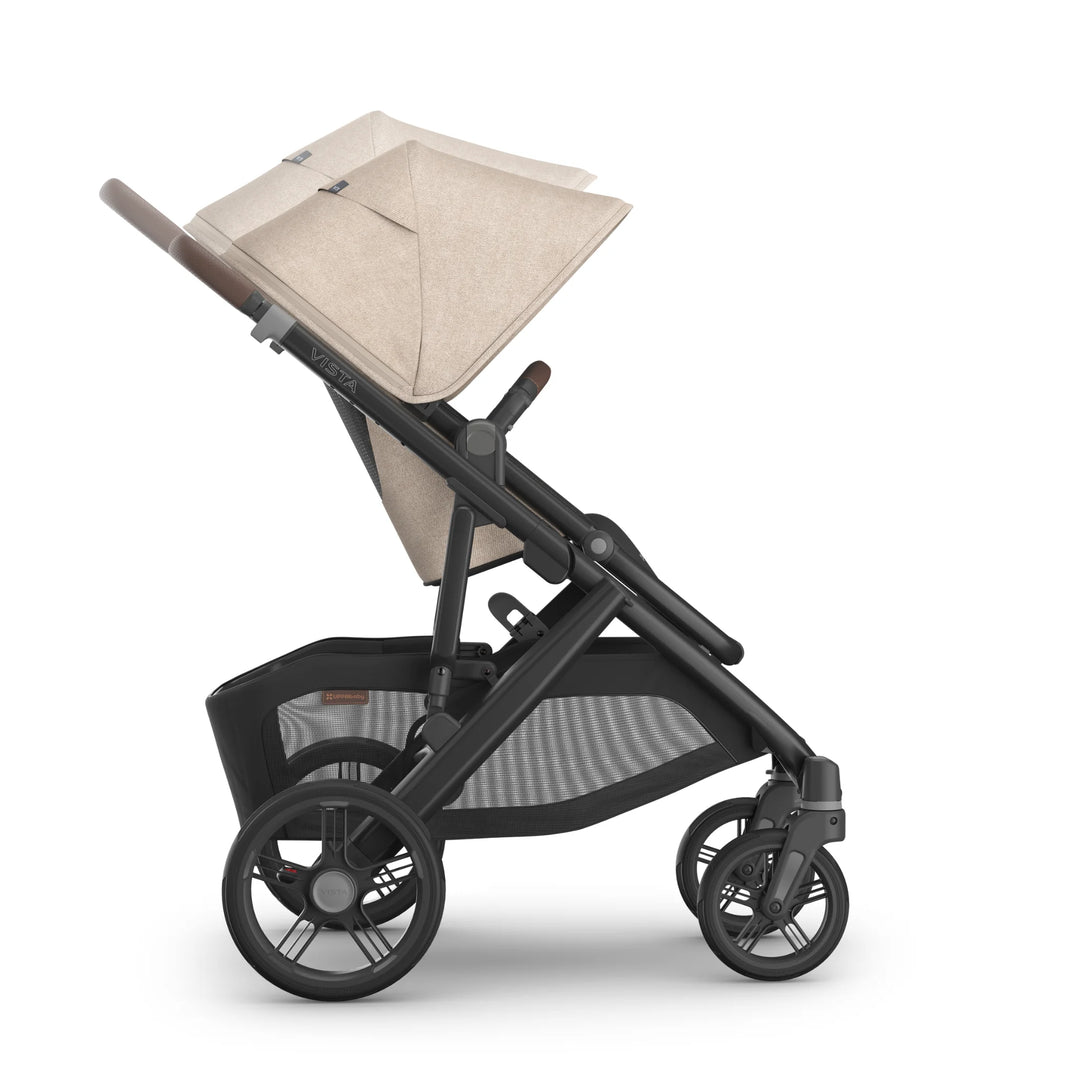 Side view of the UPPAbaby Vista V3 stroller in the Liam oatmeal colourway showing the extended canopy, adjustable leather-accented handlebar, reclining toddler seat, large under-seat storage basket and durable all-terrain wheels.