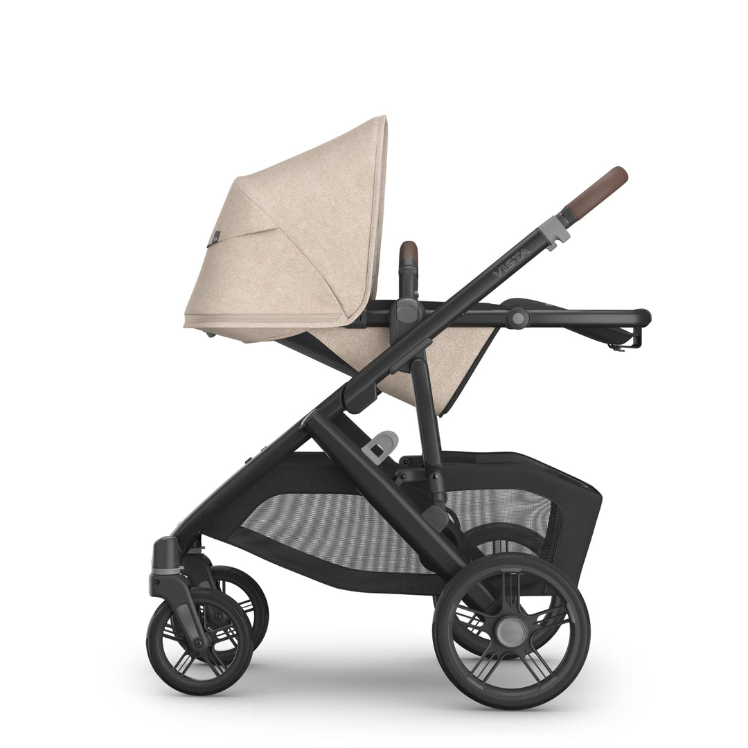 Side view of the UPPAbaby Vista V3 stroller in the Liam oatmeal colourway with the toddler seat fully reclined, showing the extended canopy, adjustable leather-accented handlebar, spacious seat design and large under-seat storage basket.