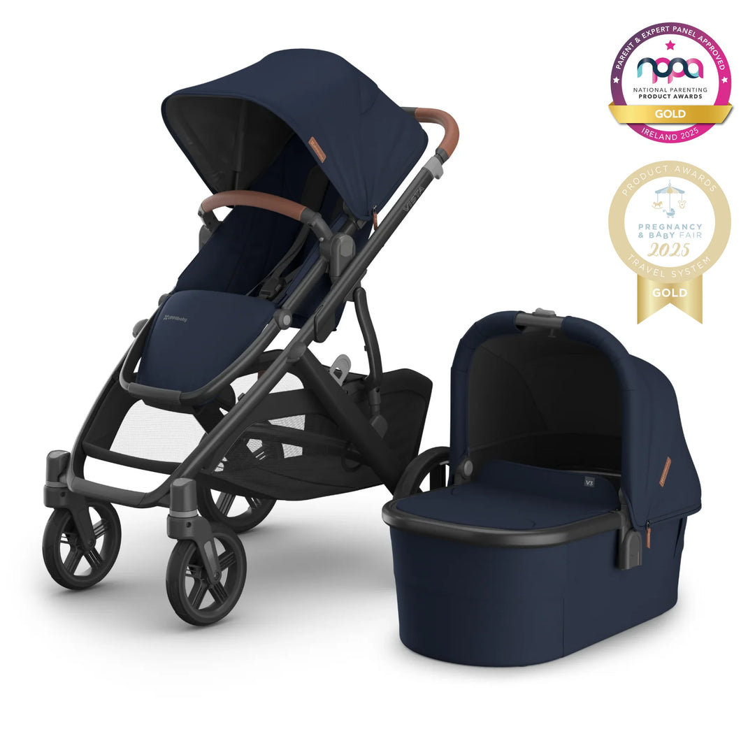 UPPAbaby VISTA V2 stroller and carrycot in navy blue with graphite frame, award-winning luxury baby travel system for newborn to toddler, featuring premium leather handlebar, large storage basket, and gold award badges from National Parenting Product Awards and Pregnancy & Baby Fair 2025.
