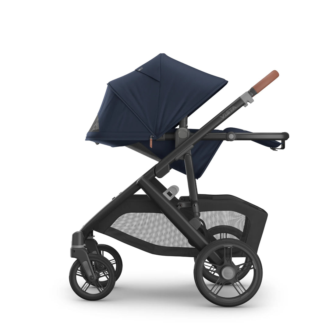 Side view of the UPPAbaby Vista V3 stroller in the Noa navy blue colourway with the toddler seat fully reclined, highlighting the extended canopy, leather-accented handlebar, ergonomic seat design, all-terrain wheels and large under-seat storage basket.