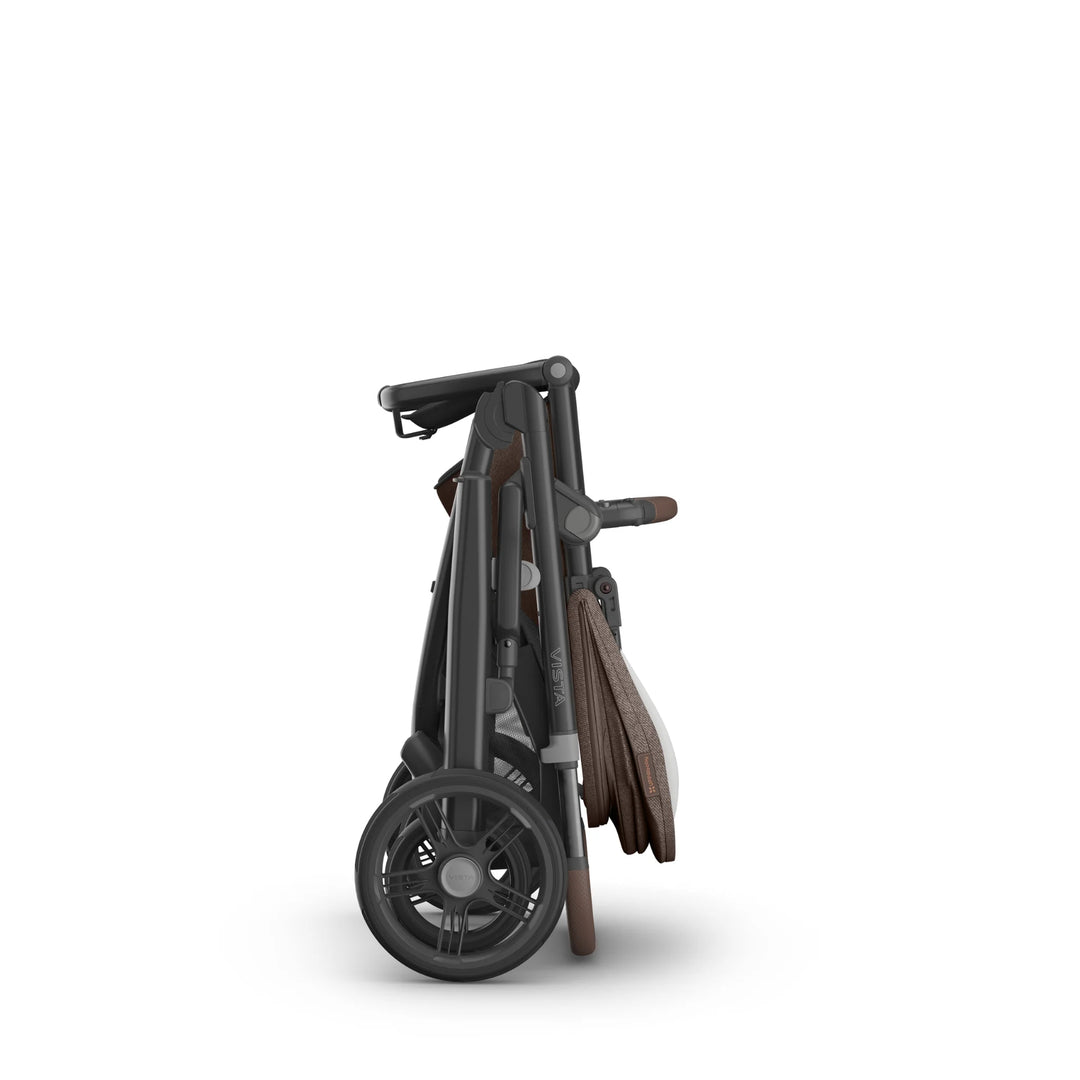 UPPAbaby Vista V3 Owen stroller folded compactly, showing the brown leather-accented handlebar, dark frame, and all-terrain wheels in an upright standing fold on a white background.