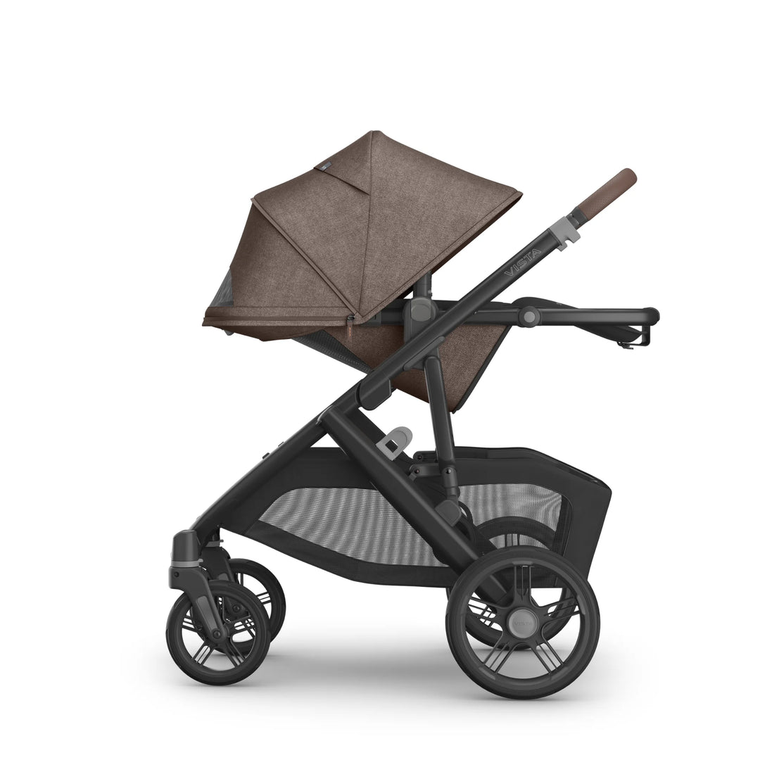 Side view of the UPPAbaby Vista V3 stroller in Owen with the toddler seat reclined and canopy fully extended, showing the brown textured fabric, adjustable handlebar, large all-terrain wheels and oversized mesh storage basket on the premium Vista travel system