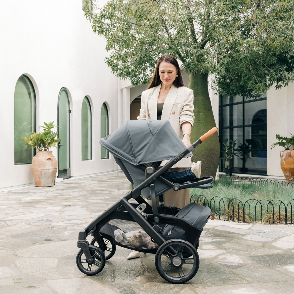 This image shows the UPPAbaby Vista V3 stroller in Dillan outdoors with a Mum extending the canopy.