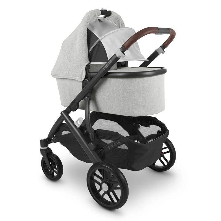 “UPPAbaby Vista V2 Anthony travel system with carrycot in light grey fabric and brown leather handle, featuring black frame, large storage basket, and smooth all-terrain wheels — luxury newborn pram and pushchair combo.