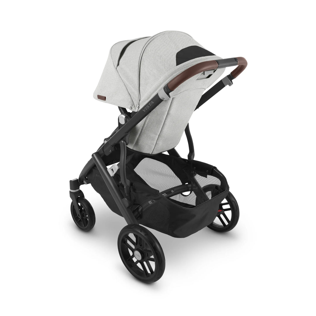 Rear view of UPPAbaby Vista V2 Anthony stroller in light grey fabric with brown leather handlebar, showing large storage basket and sturdy all-terrain wheels — premium pushchair designed for modern parents.