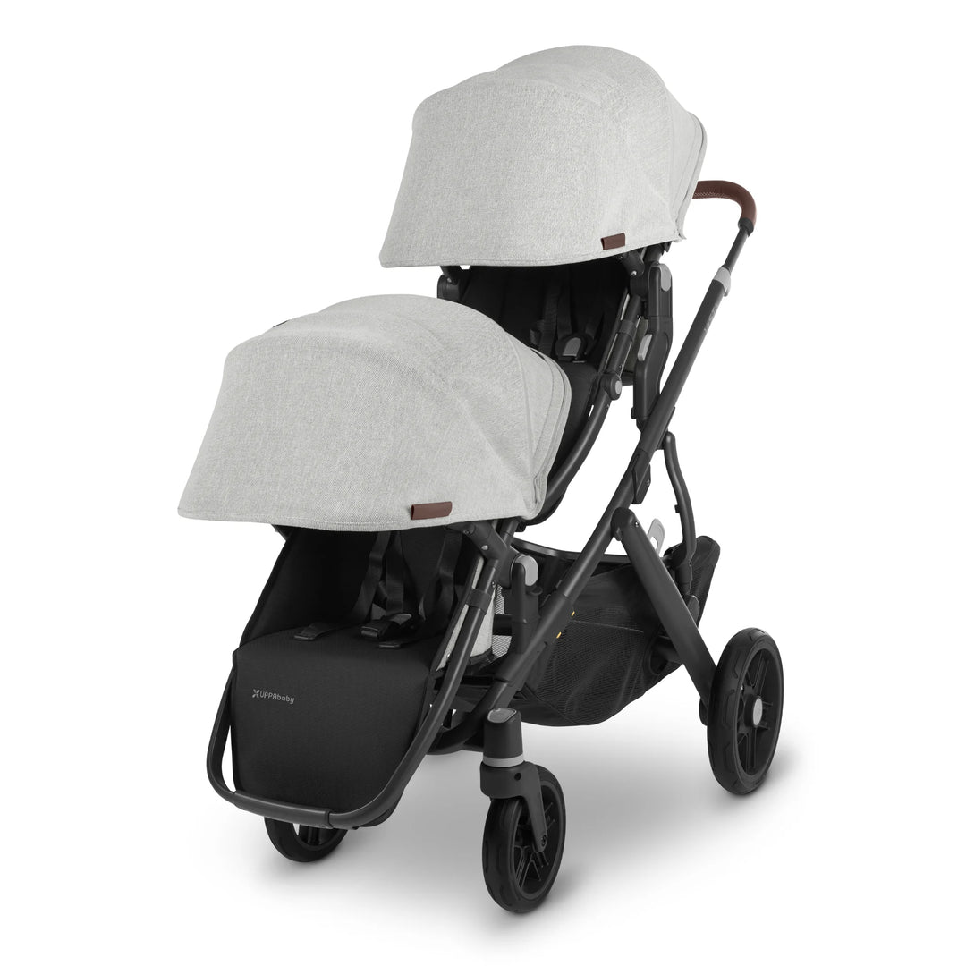 UPPAbaby Vista V2 Anthony double pushchair in light grey fabric with black frame and brown leather handle, featuring two toddler seats with extendable canopies and large underseat basket — versatile tandem stroller for growing families.