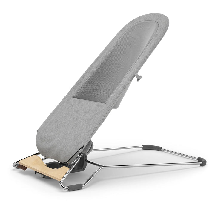 UPPAbaby Mira Bouncer in Stella grey shown in semi-upright angled view, featuring breathable mesh seat, ergonomic infant support design, adjustable recline, and sleek lightweight frame with natural wood base accent.