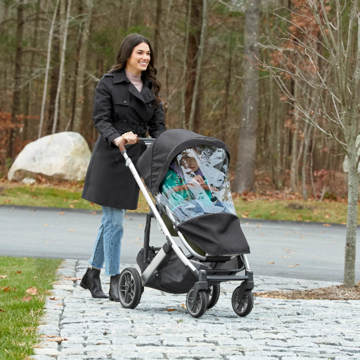 Parent pushing UPPAbaby Vista V3 stroller outdoors with UPPAbaby Performance Rain Shield fitted, keeping child dry and protected from rain and wind.