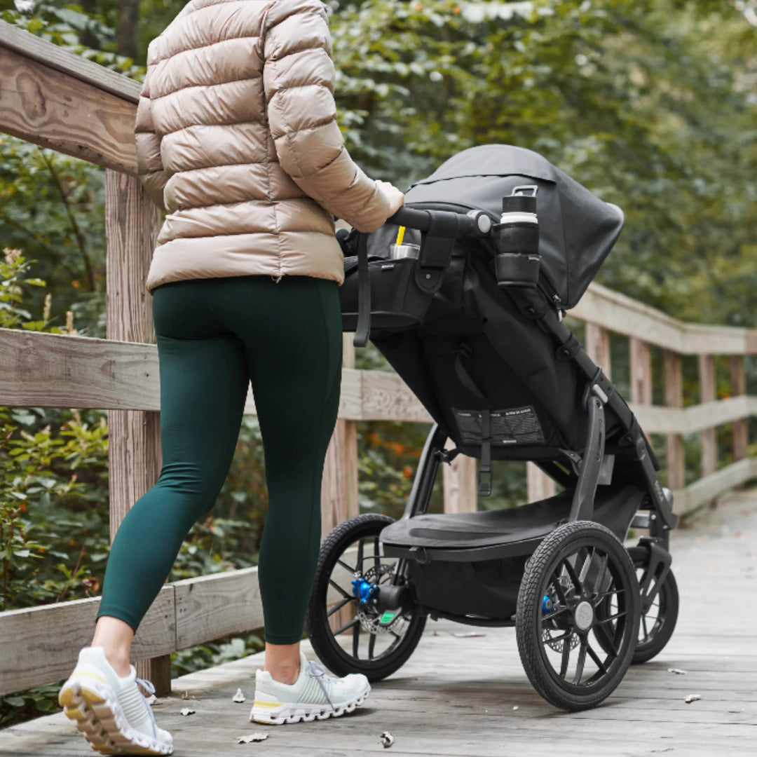 UPPAbaby RIDGE stroller with collapsible cup holder attached, being pushed on a boardwalk