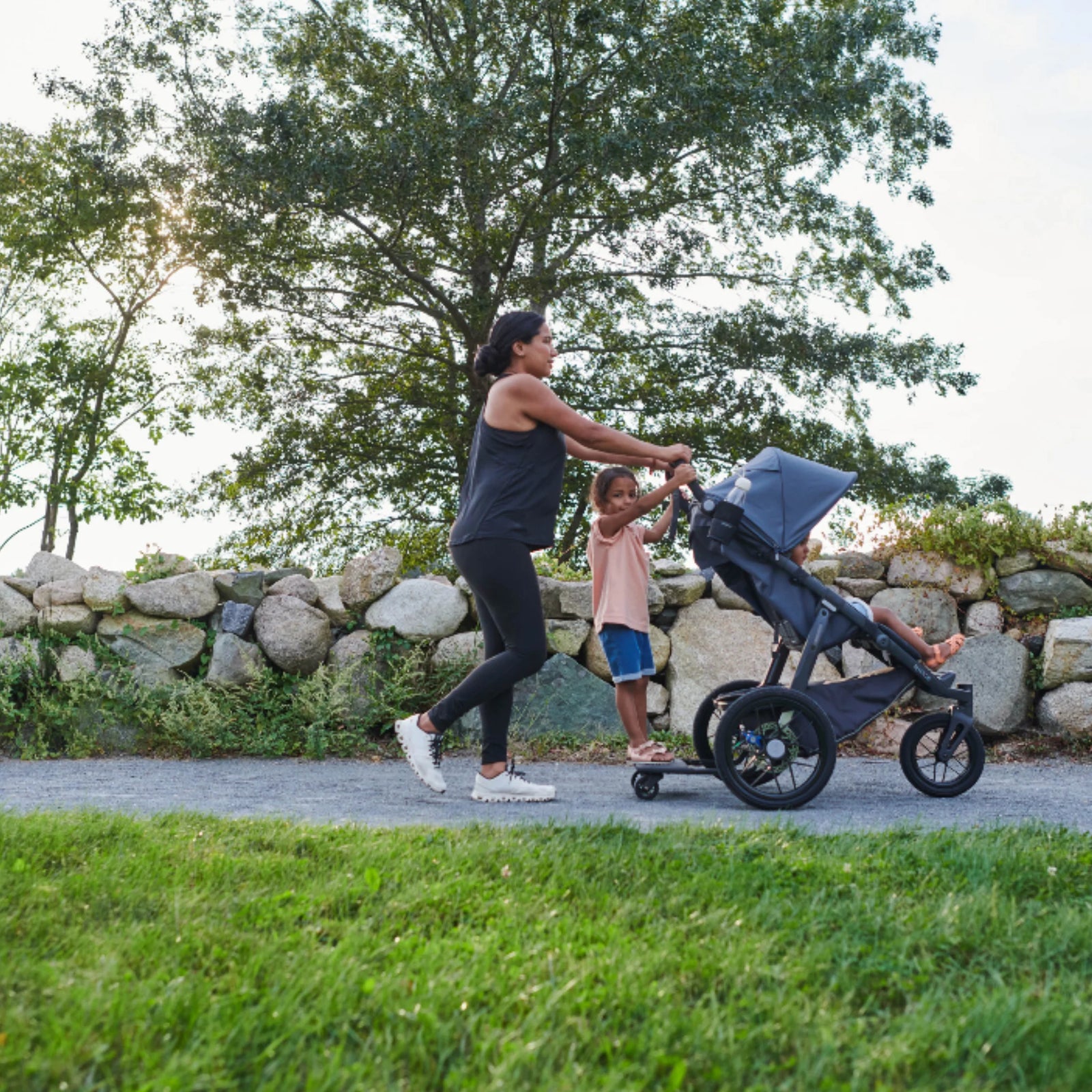 “UPPAbaby RIDGE jogging stroller with PiggyBack ride-along board, parent and child walking on a park path”